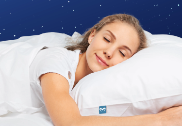 Kvinde, der sover på siden med kinden på en MelaSleep pude